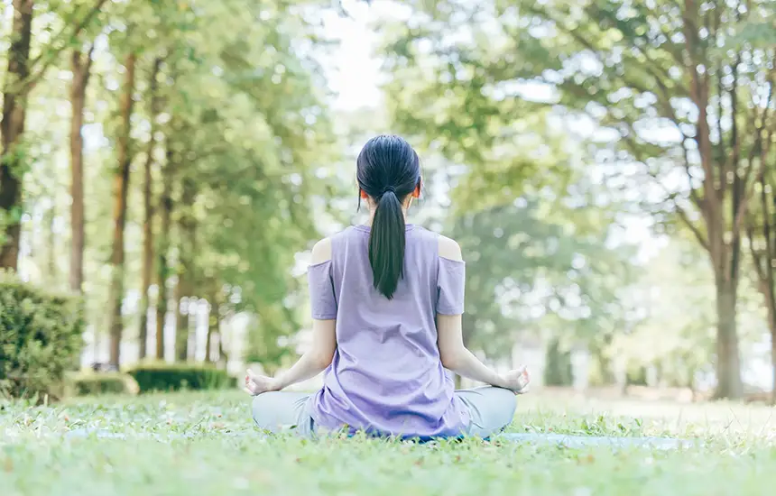 Woman meditating in nature during a forest bathing and wellness experience in Japan