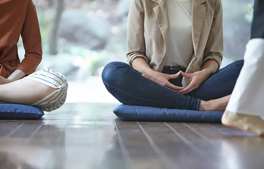 Zazen meditation posture with hands in Zen mudra on temple floor.