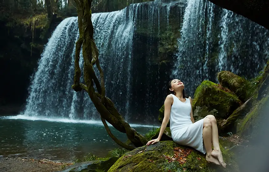 People relaxing near a moss-covered waterfall.
