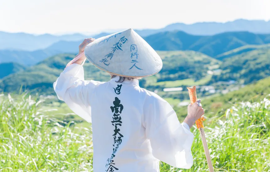 People in pilgrim attire walking through a rural landscape.